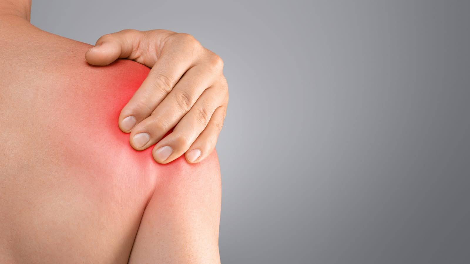 A hand grasps a bare shoulder with a red glow indicating pain.